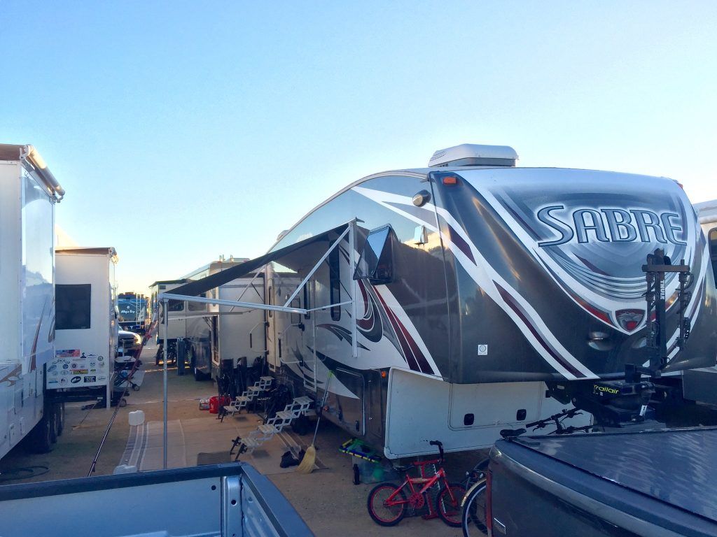 RVs parked side-by-side in an outdoor setting, one has an awning extended.