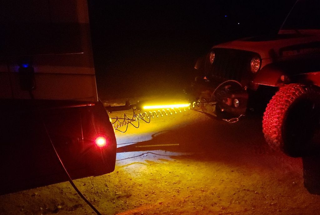 A jeep is parked next to a trailer at night.