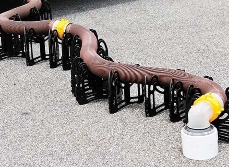 Flexible black and brown ducting laid across a floor, connected to a white vacuum unit.