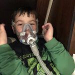 A young boy is wearing an oxygen mask on his face.