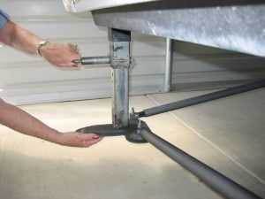 A person is adjusting a metal pole with a wrench.