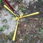 A yellow pole with a hook attached to it is laying on the ground.