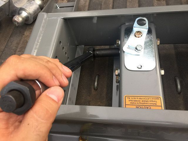 A person is holding a screwdriver over a piece of metal.