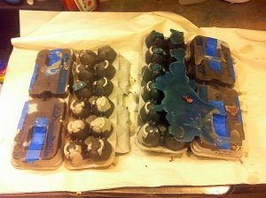 Two egg cartons are sitting on a table next to each other.