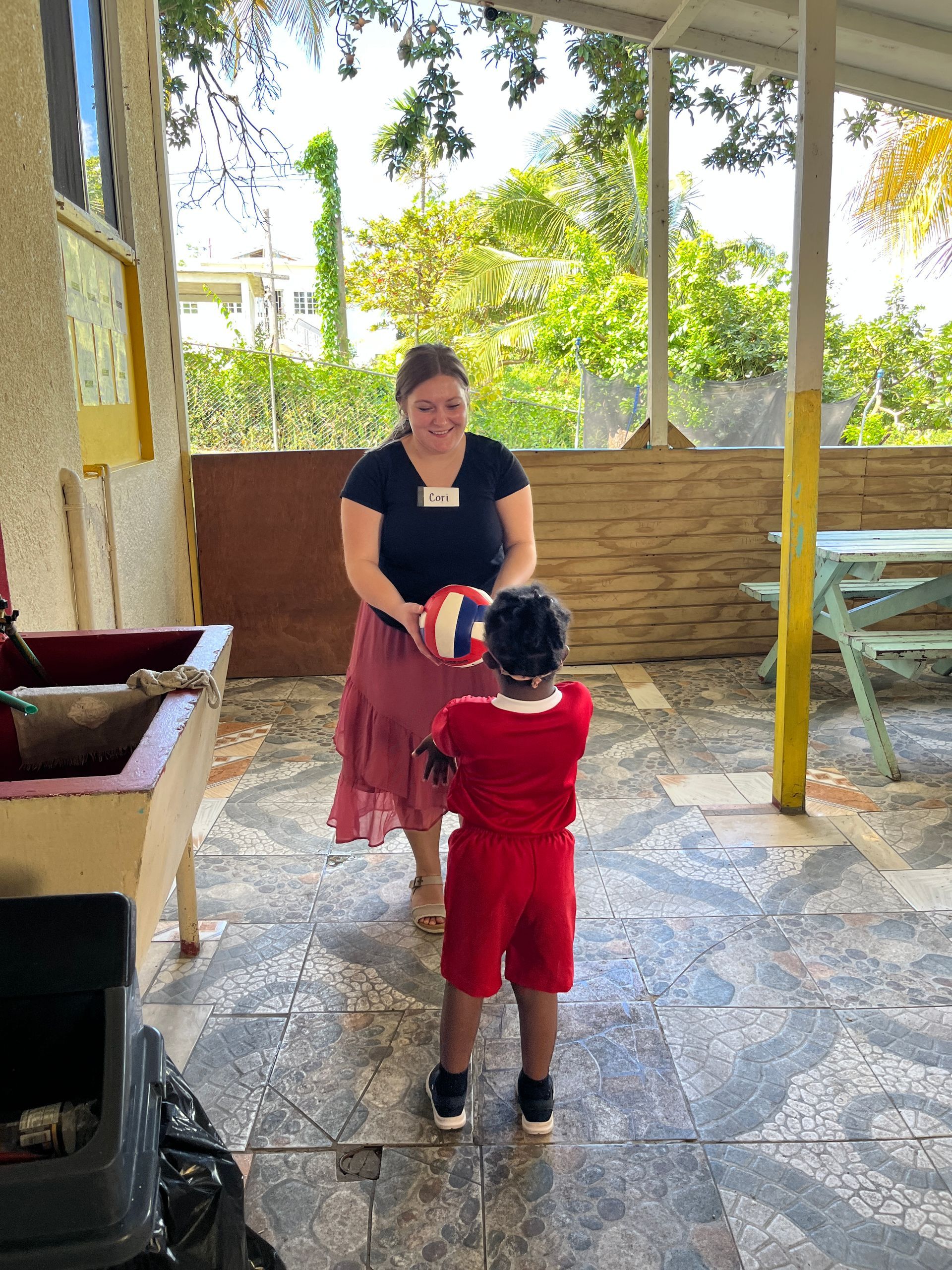 A woman is standing next to a child holding a ball.