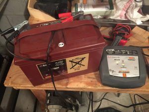A battery is sitting on top of a wooden table next to a charger.