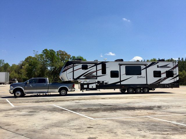 A truck is towing a trailer in a parking lot.