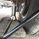 A close up of a person standing next to a motorcycle wheel.