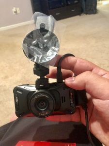 A person is holding a dash cam in their hand.