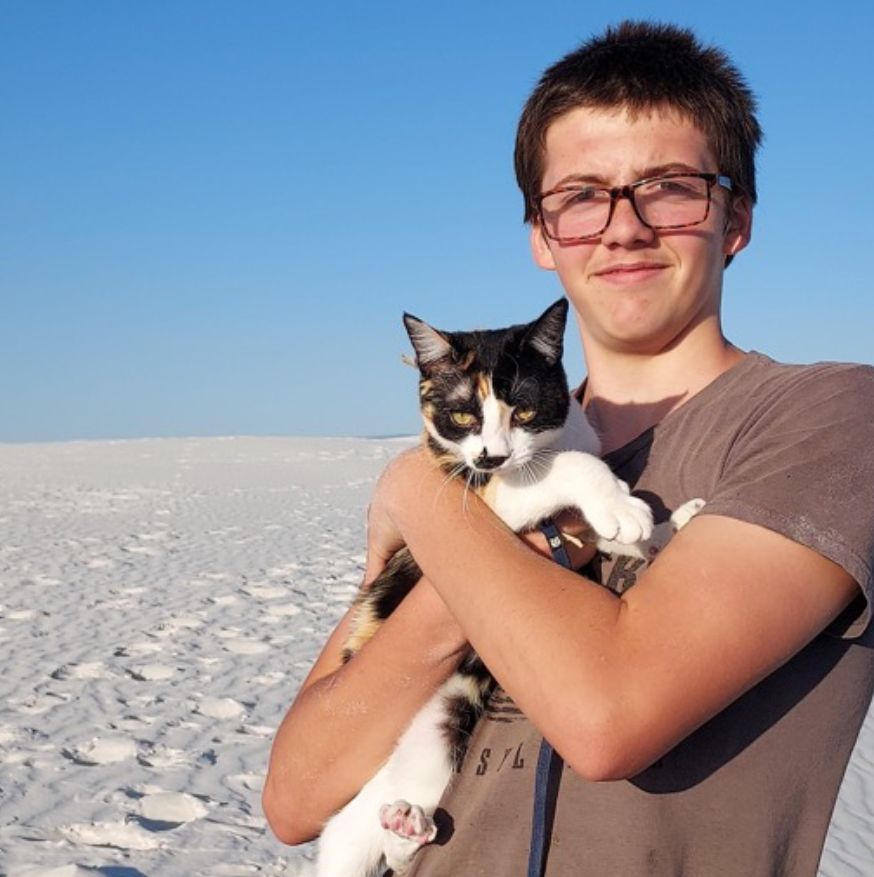 A man wearing glasses holds a cat in his arms