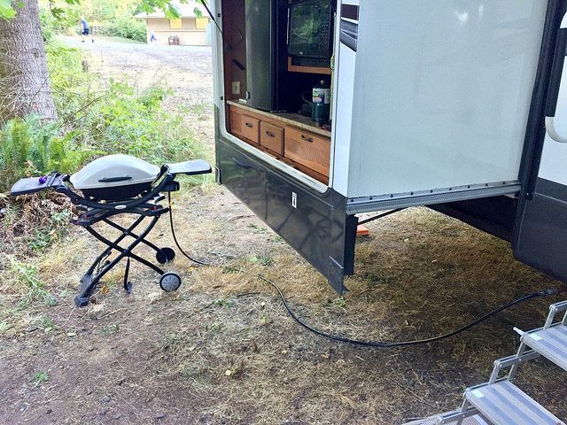 A rv with a grill attached to the side of it.