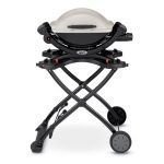 A grill is sitting on top of a folding stand.