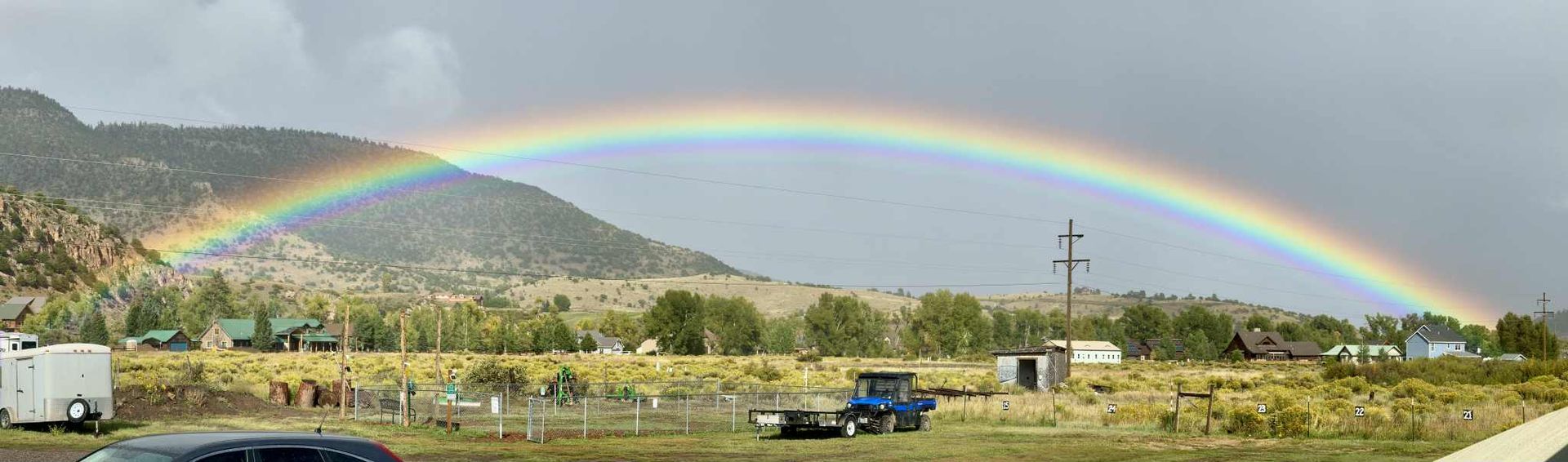 A double rainbow is visible over a field of sunflowers