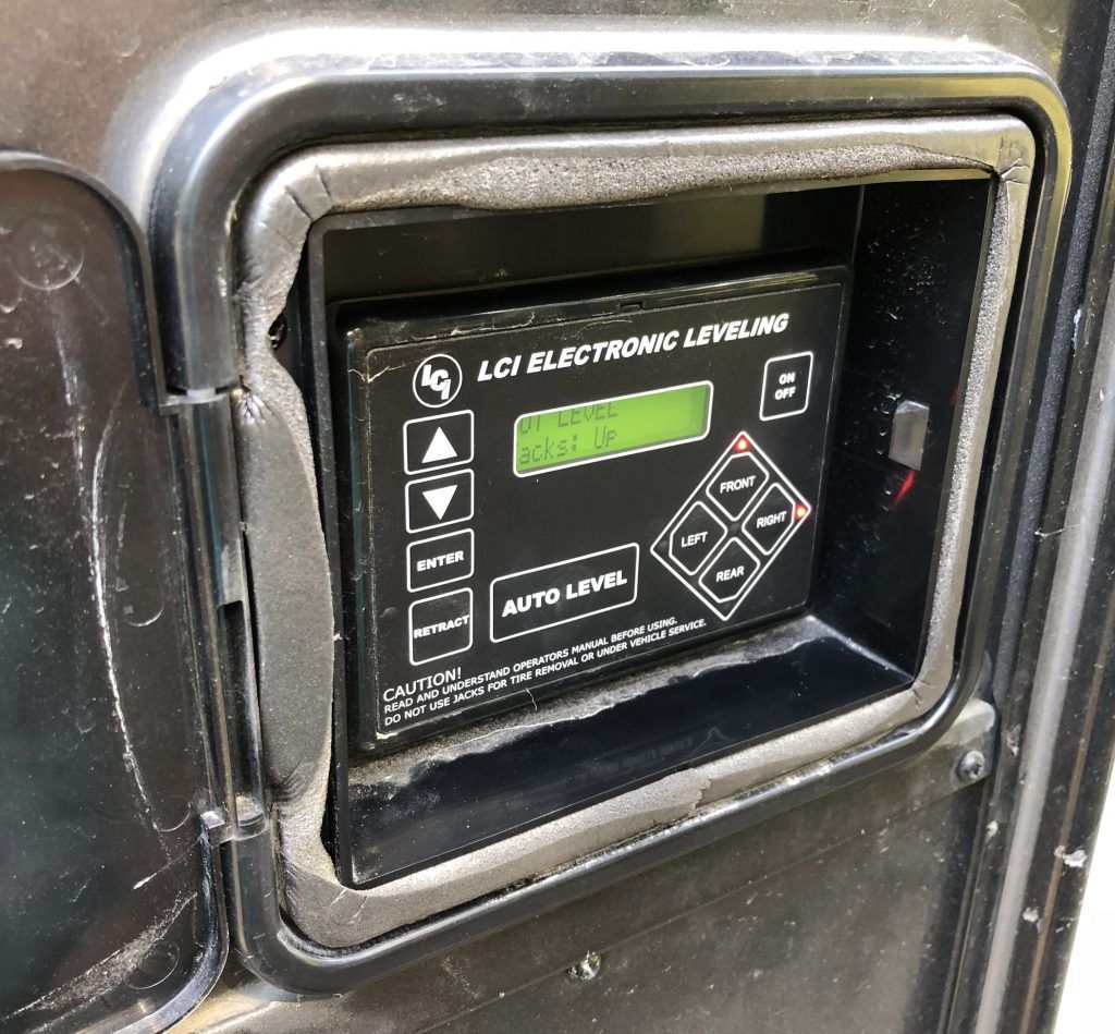 LCI Electronic Leveling control panel in black casing with buttons and display on a recreational vehicle.