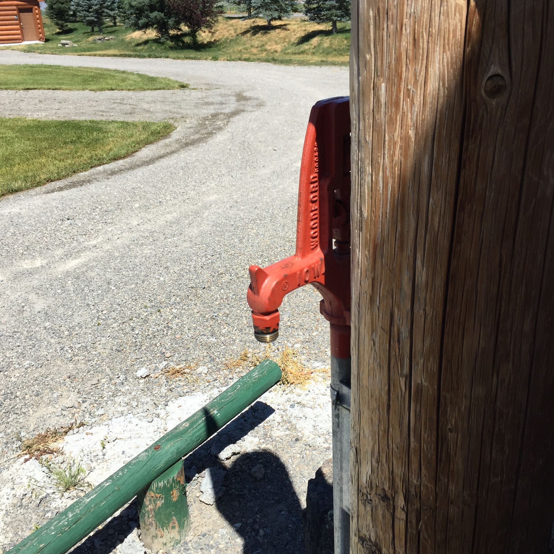 A red faucet is attached to a wooden pole