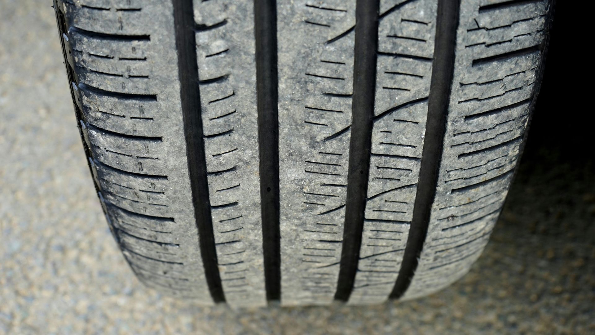 Close-up of a car tire tread with vertical and angled grooves, showing wear.