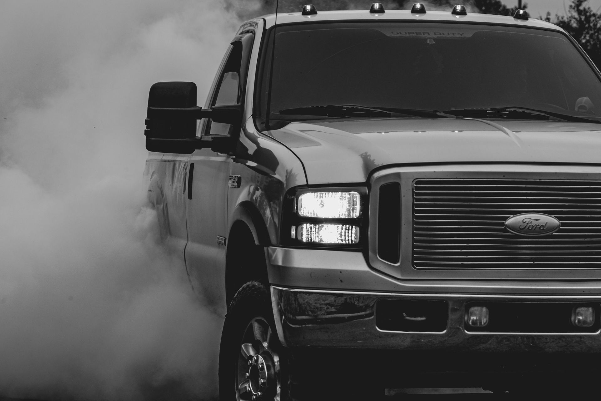 Black pickup truck driving through smoke, front view on a road