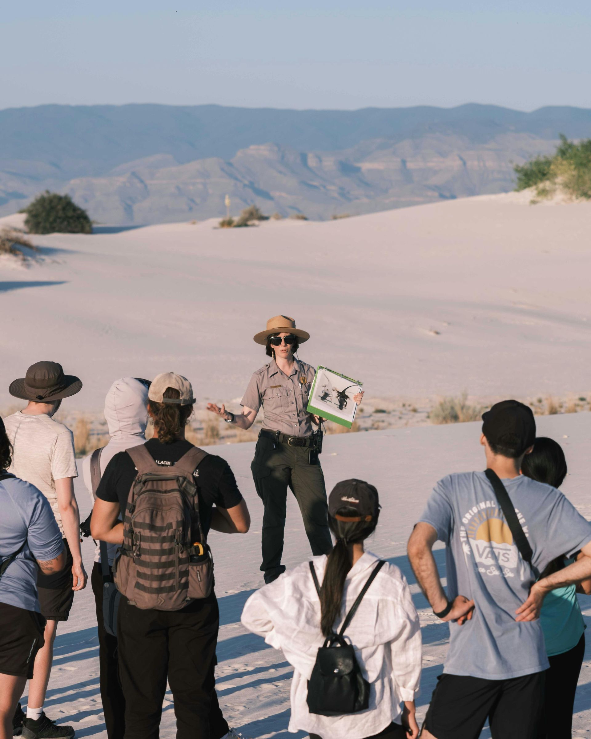 Park ranger leading a group on a tour in white sand dunes.