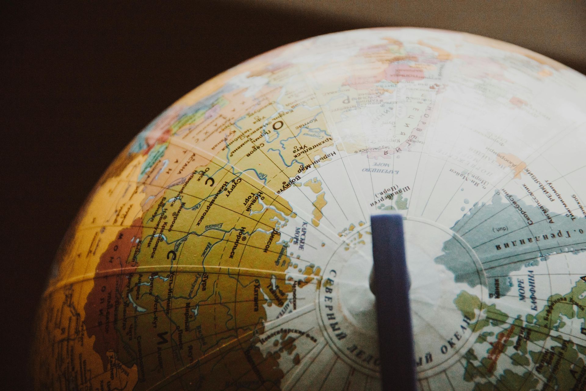 A close up of a globe with a pen sticking out of it.