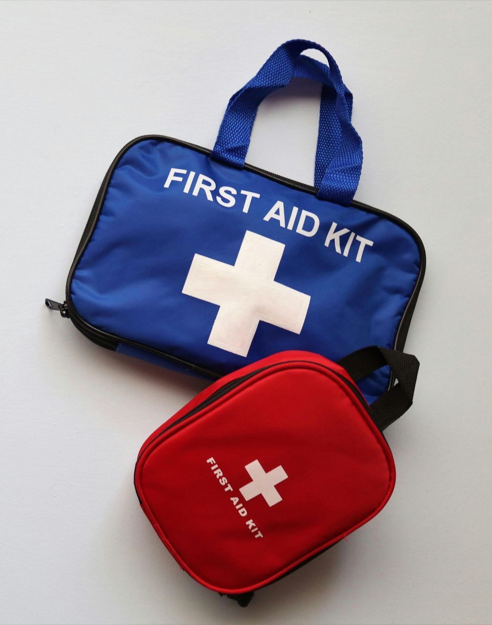 Two first aid kits, one blue and one red, both with white crosses.