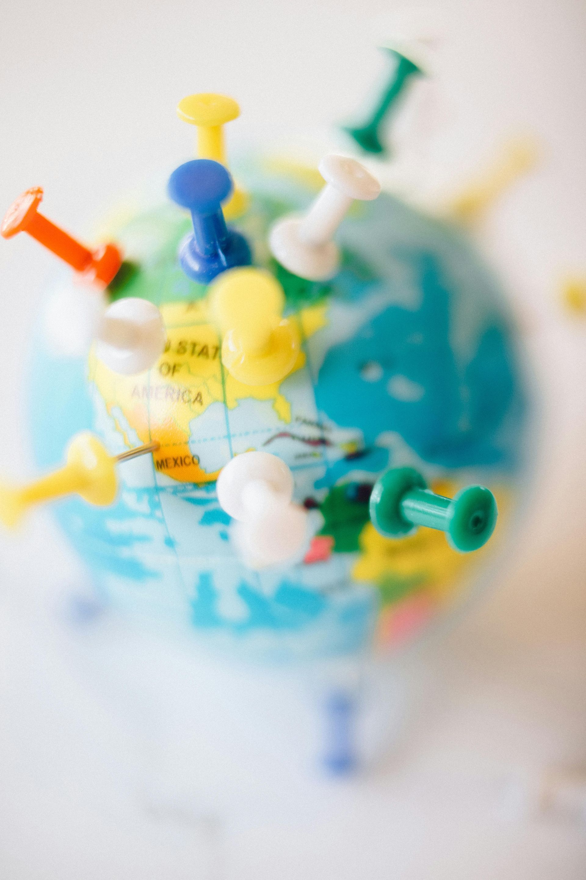 A small globe with colorful pushpins stuck in it.