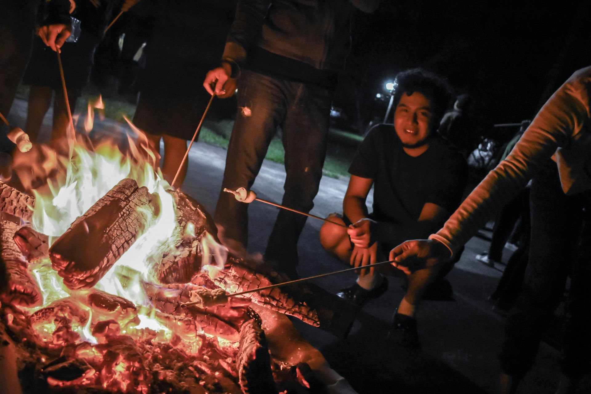 People roasting marshmallows over a bonfire at night.