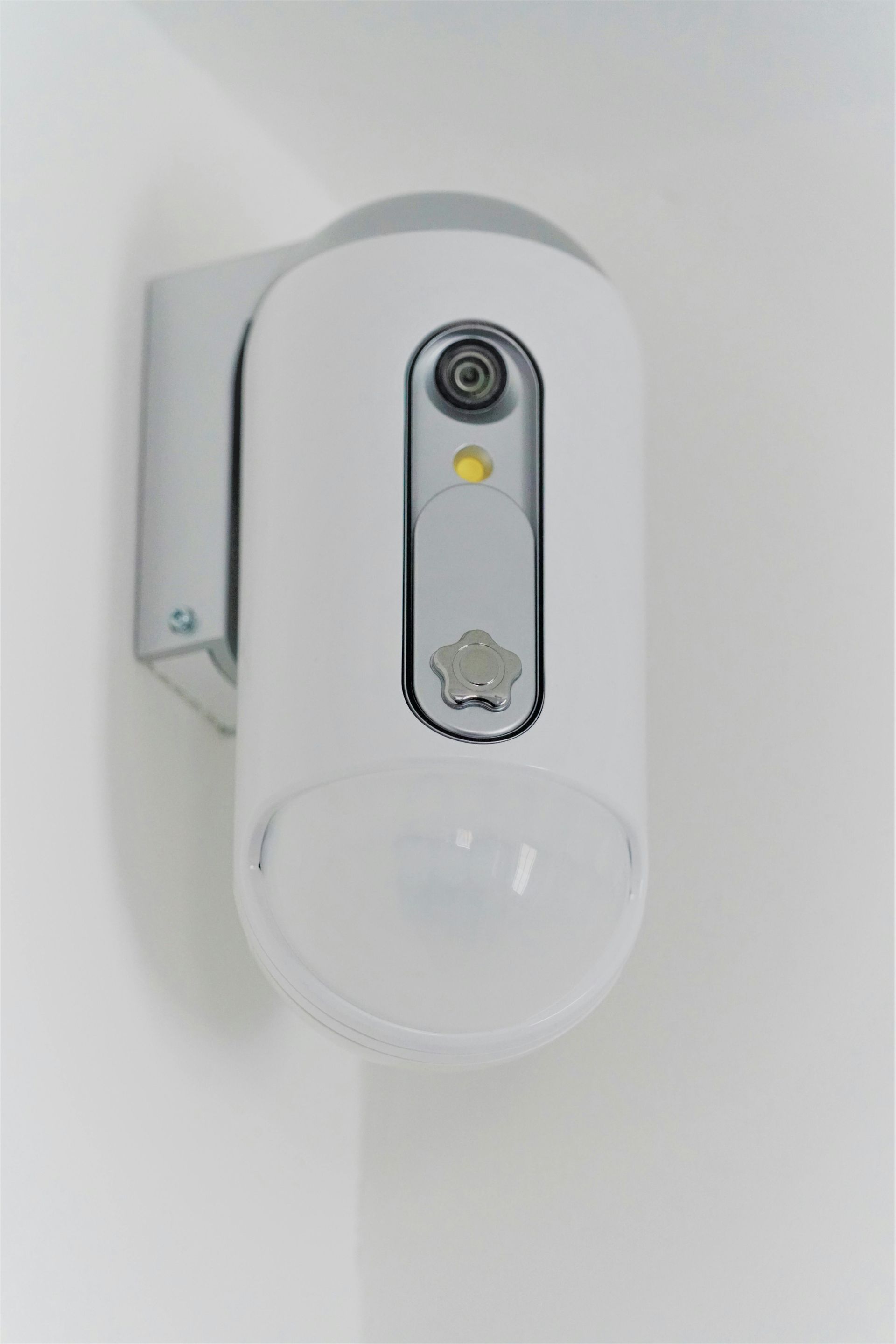White wall-mounted security camera with a dome lens and status light.