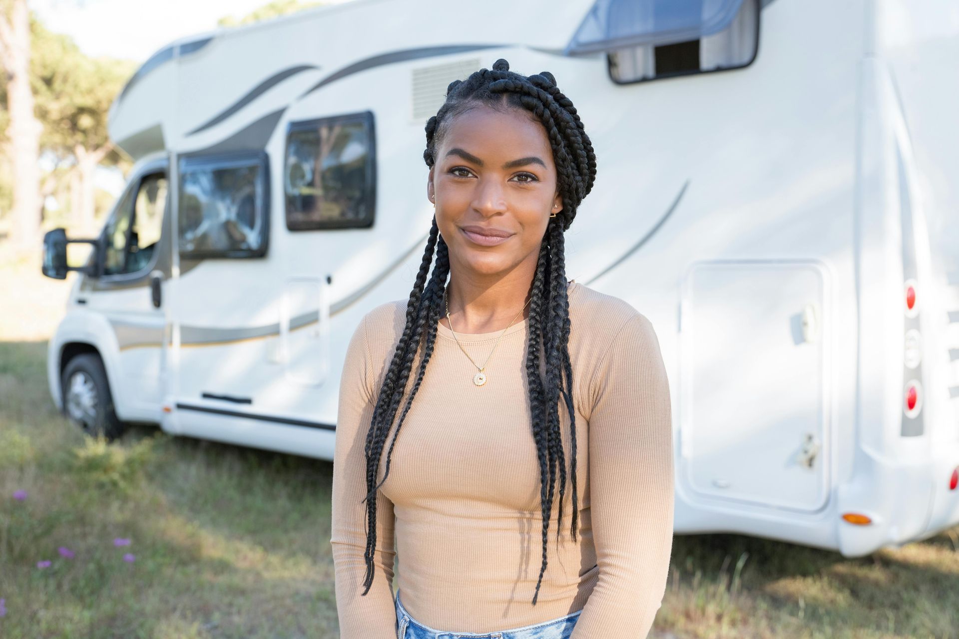 Woman with long braids stands in front of a white RV.