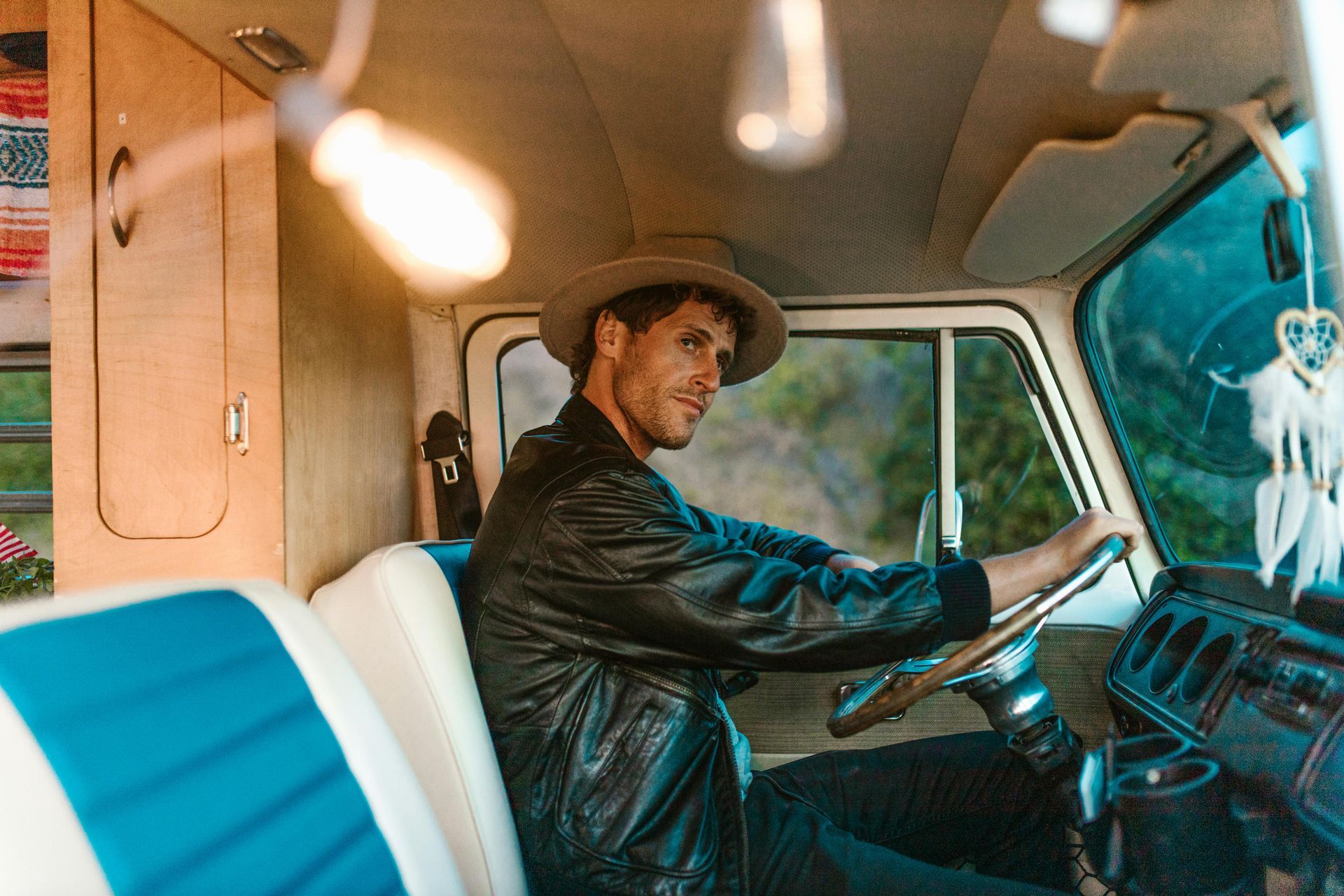 A man in a hat is sitting in the driver 's seat of a van.