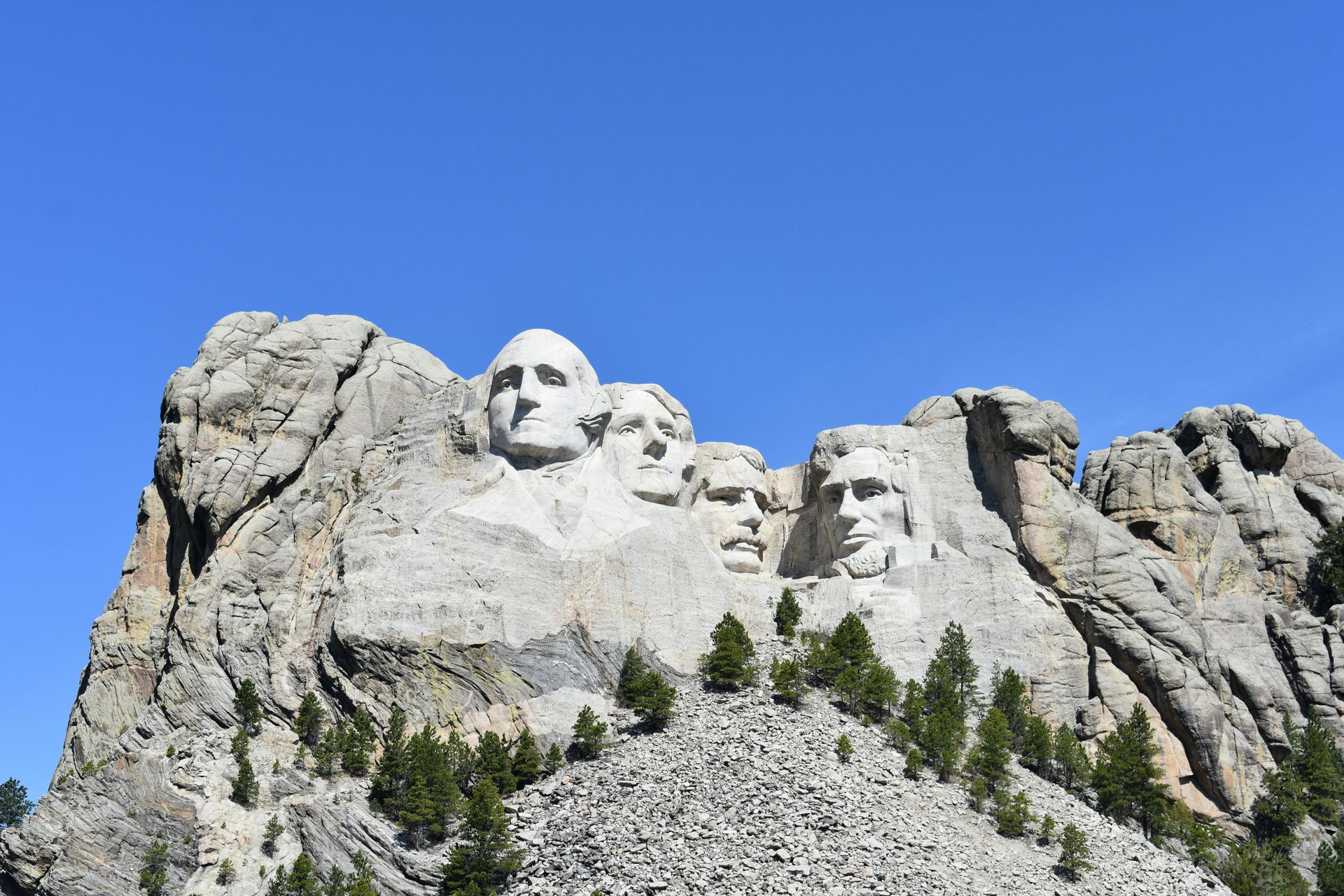 Mount Rushmore National Memorial in South Dakota with four presidents carved in stone against a blue sky.