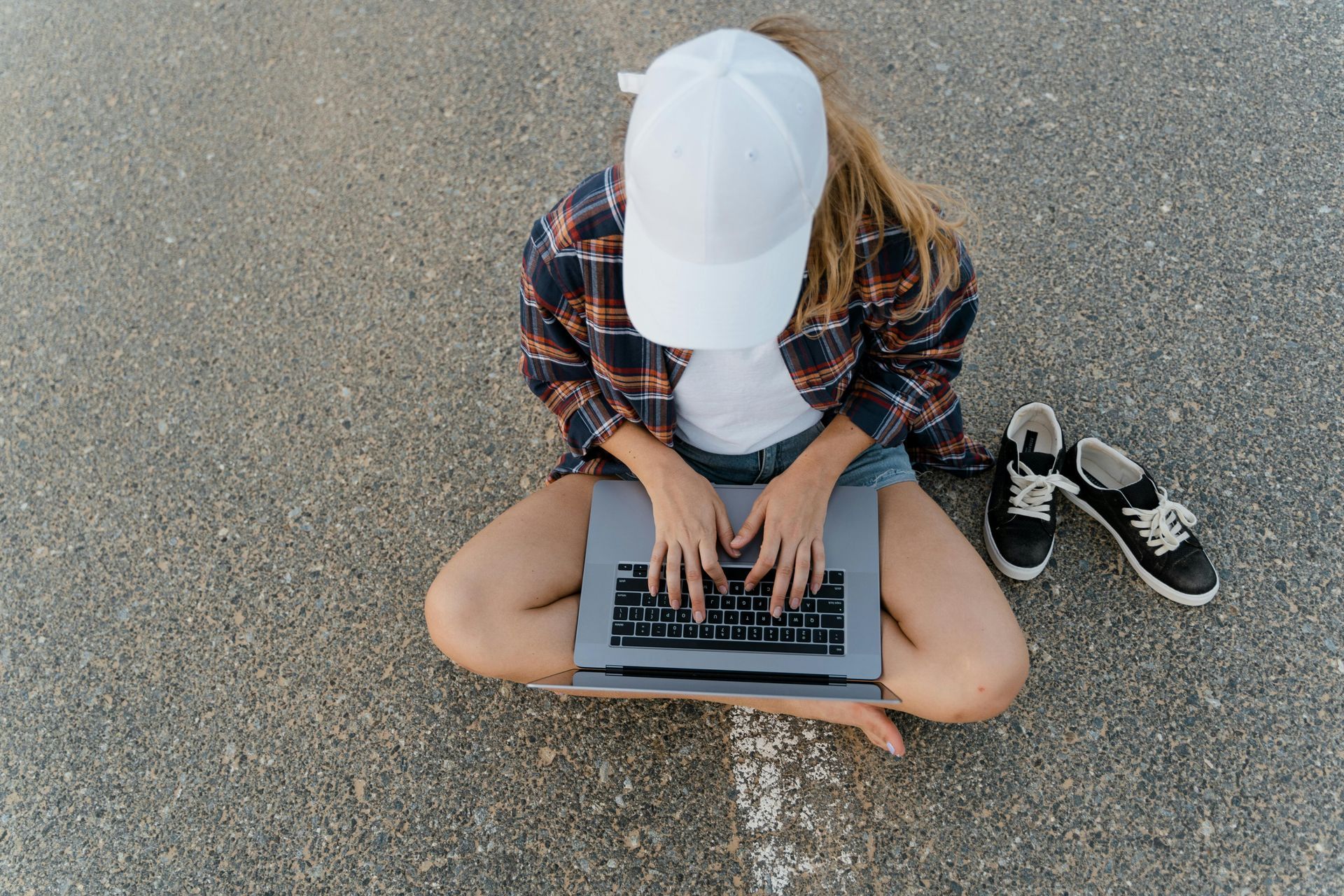A woman is sitting on the ground using a laptop computer.
