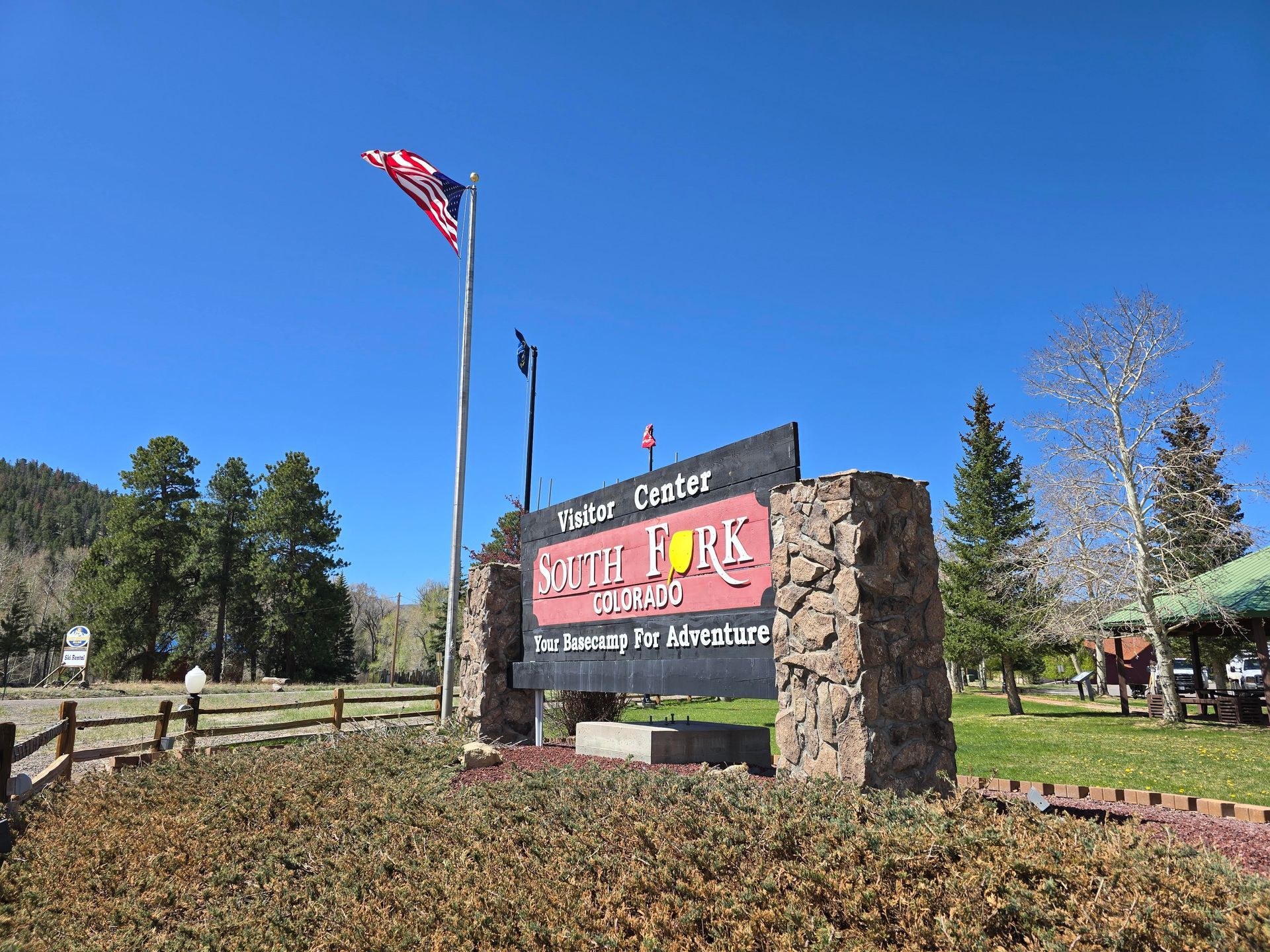 A sign for a park with a flag flying in the background.