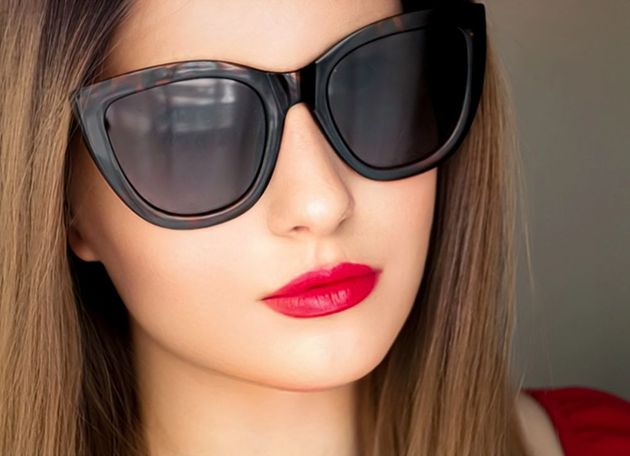 Donna con grandi occhiali da sole neri, rossetto rosso e capelli biondi.