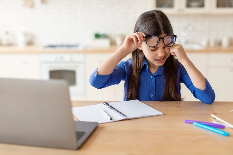 Famiglia che sceglie gli occhiali in un negozio di ottica. La madre indica, il figlio indossa gli occhiali, l'ottico aiuta.