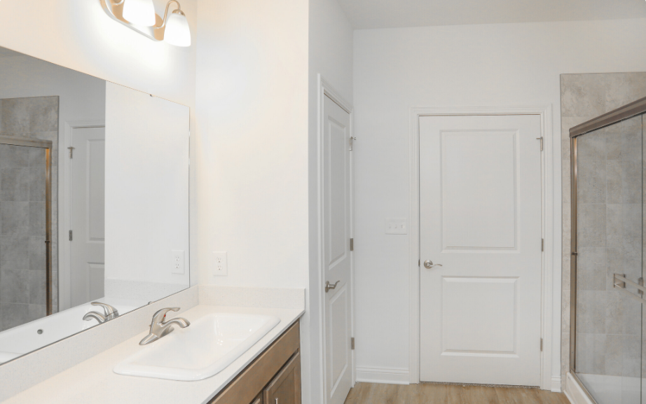 Shows the bathroom vanity, large mirror, and stand up shower