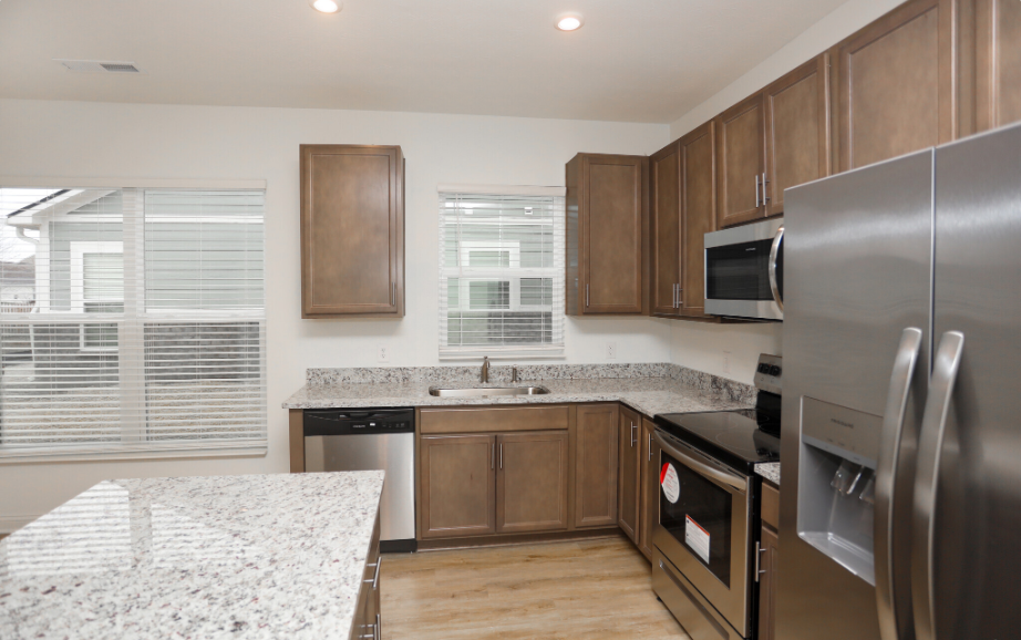 Modern kitchen with brown cabinets, an oven, dishwasher, and fridge