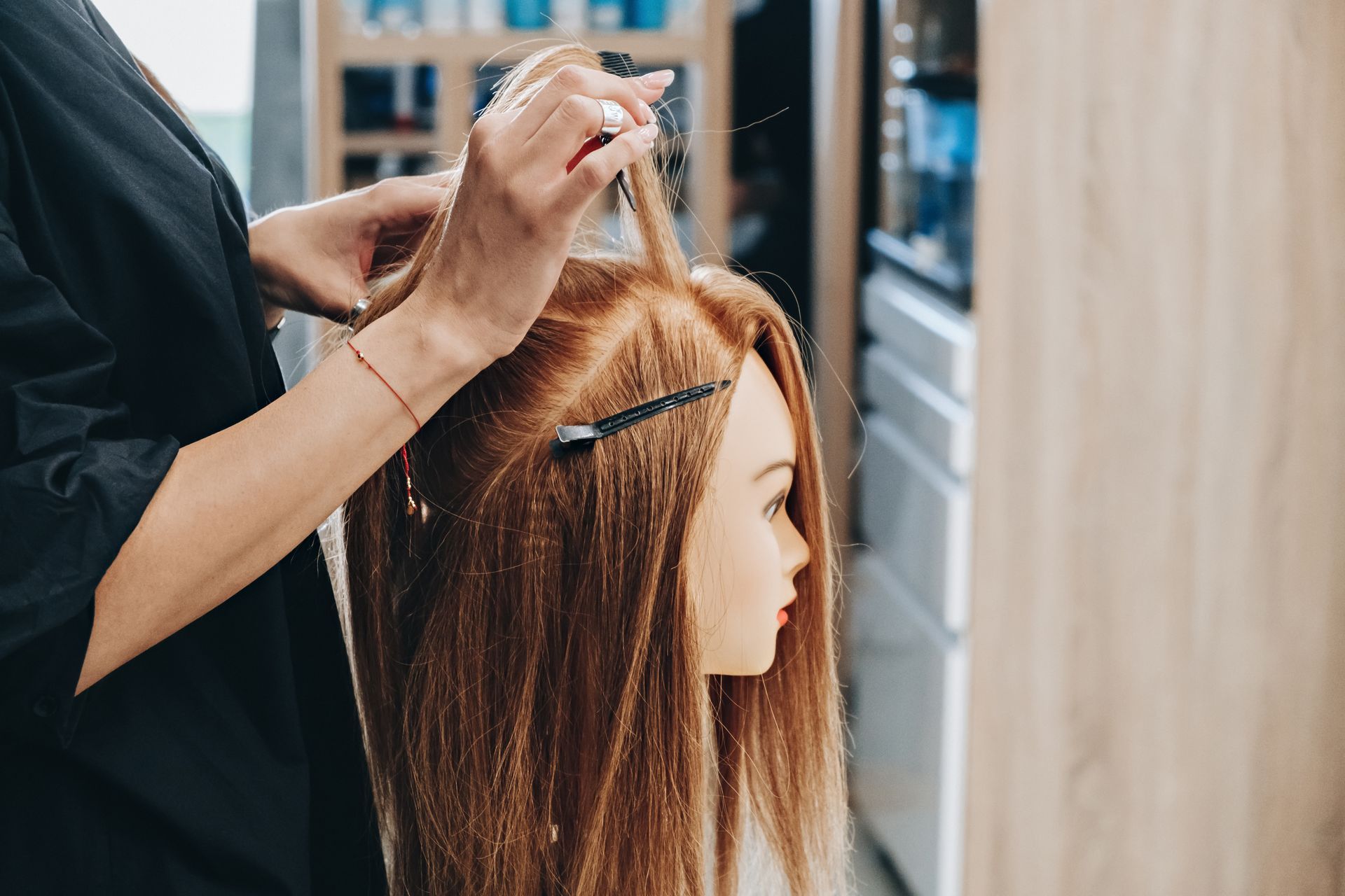 A person styling a mannequin's long, light brown hair in a salon setting. A person styling a mannequin's long, light brown hair in a salon setting.