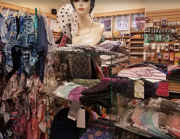 Makeup and hats on display in a store. Shelves hold lipsticks, compacts, and various colored hats. Makeup and hats on display in a store. Shelves hold lipsticks, compacts, and various colored hats.