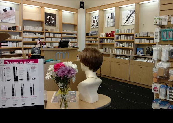 Beauty store interior with product displays, a wig on a mannequin, and a mascara index poster.