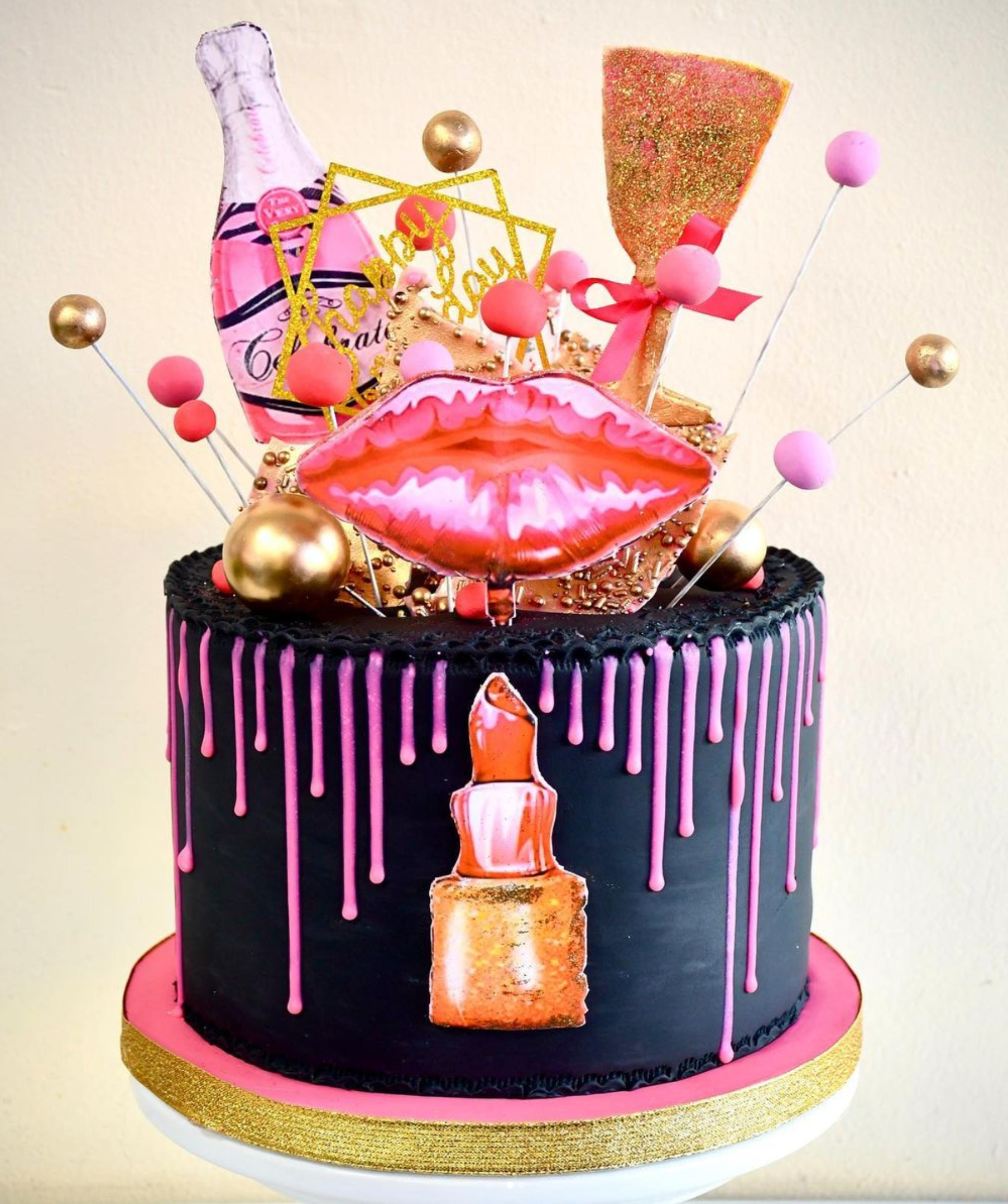 A birthday cake with a bottle of champagne and a lipstick on it