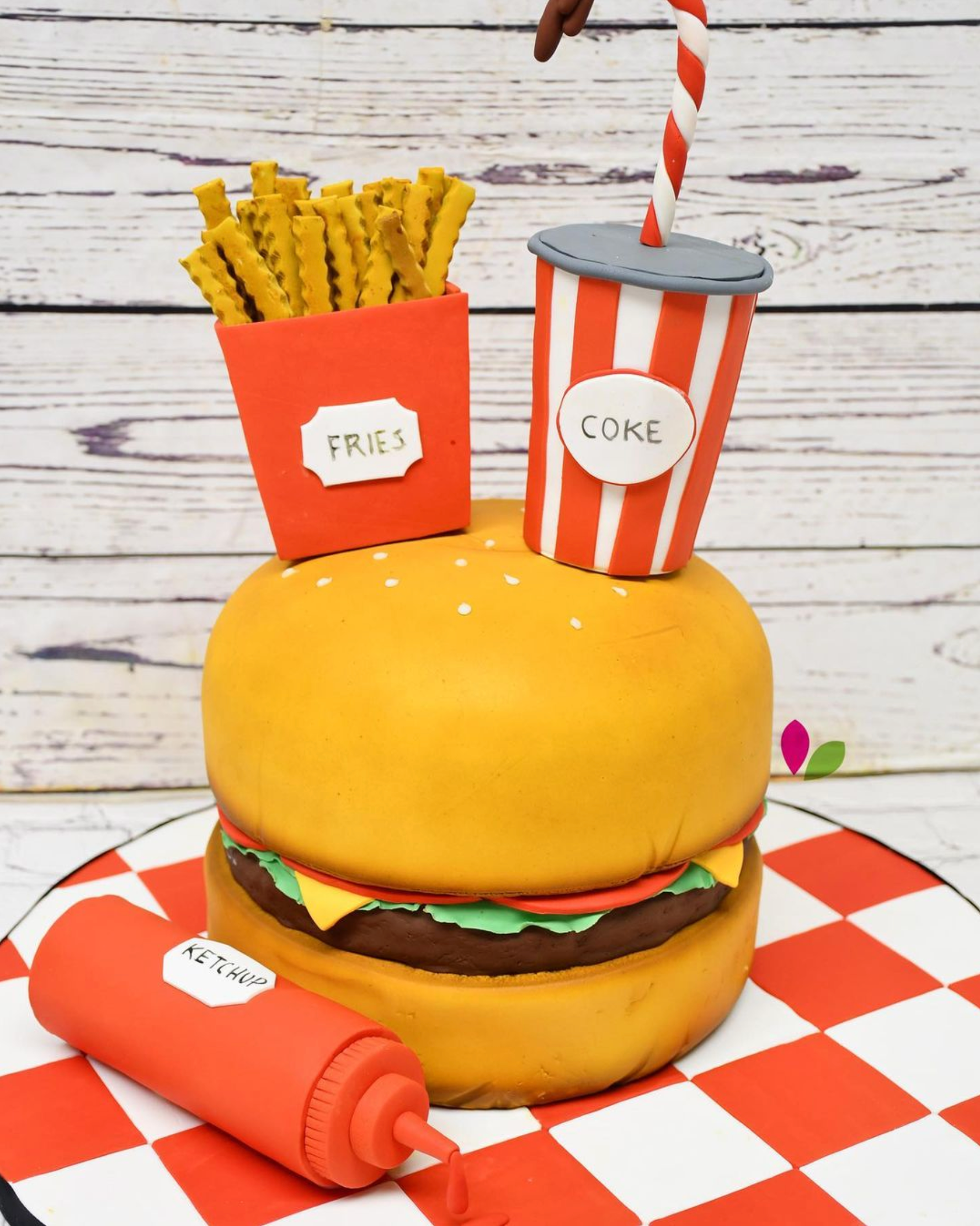 A cake in the shape of a hamburger with french fries and a soda