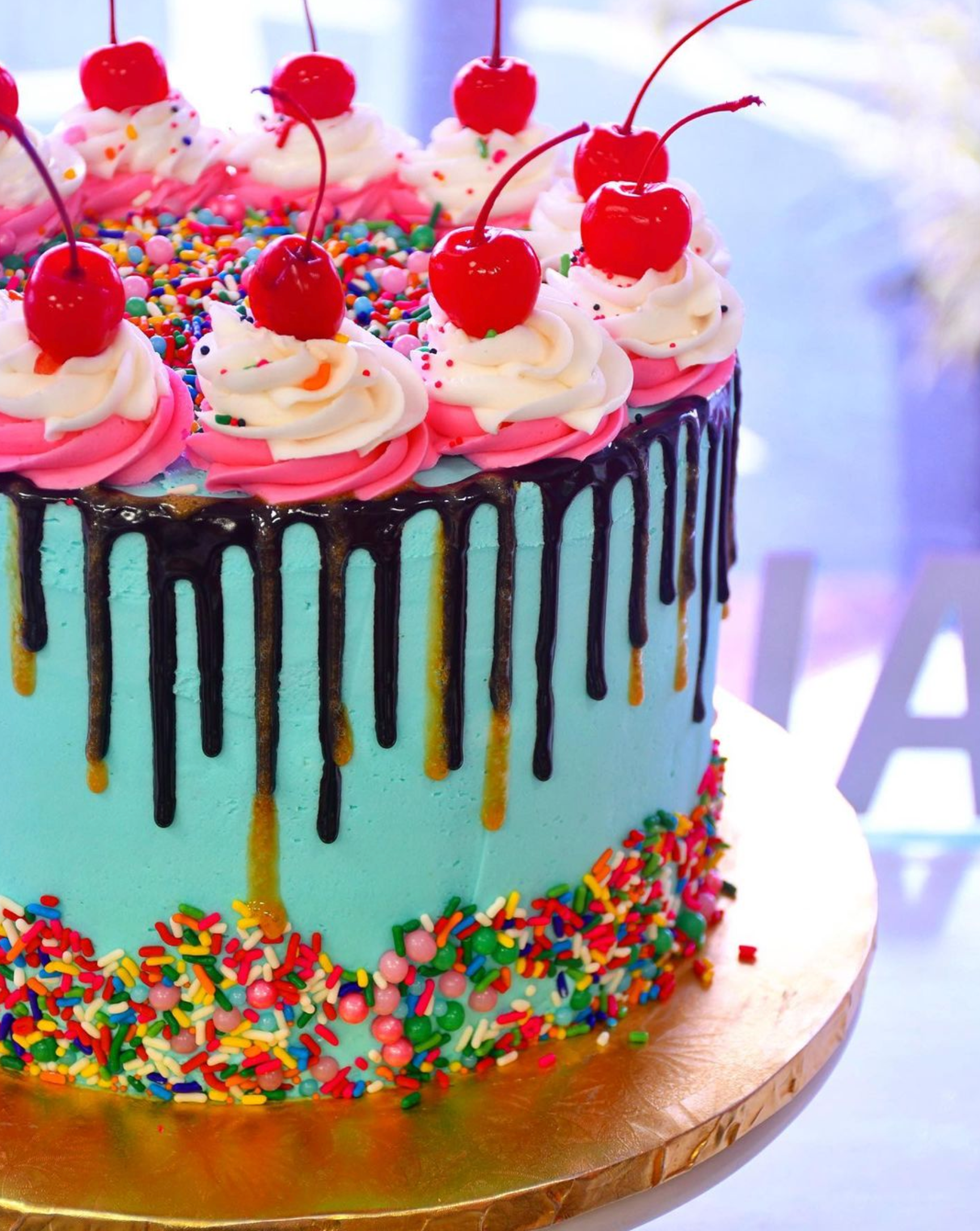 A blue cake with pink frosting and cherries on top