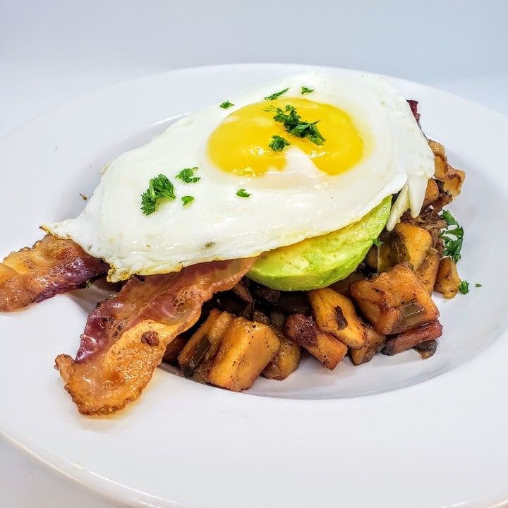 A white plate topped with eggs bacon and potatoes