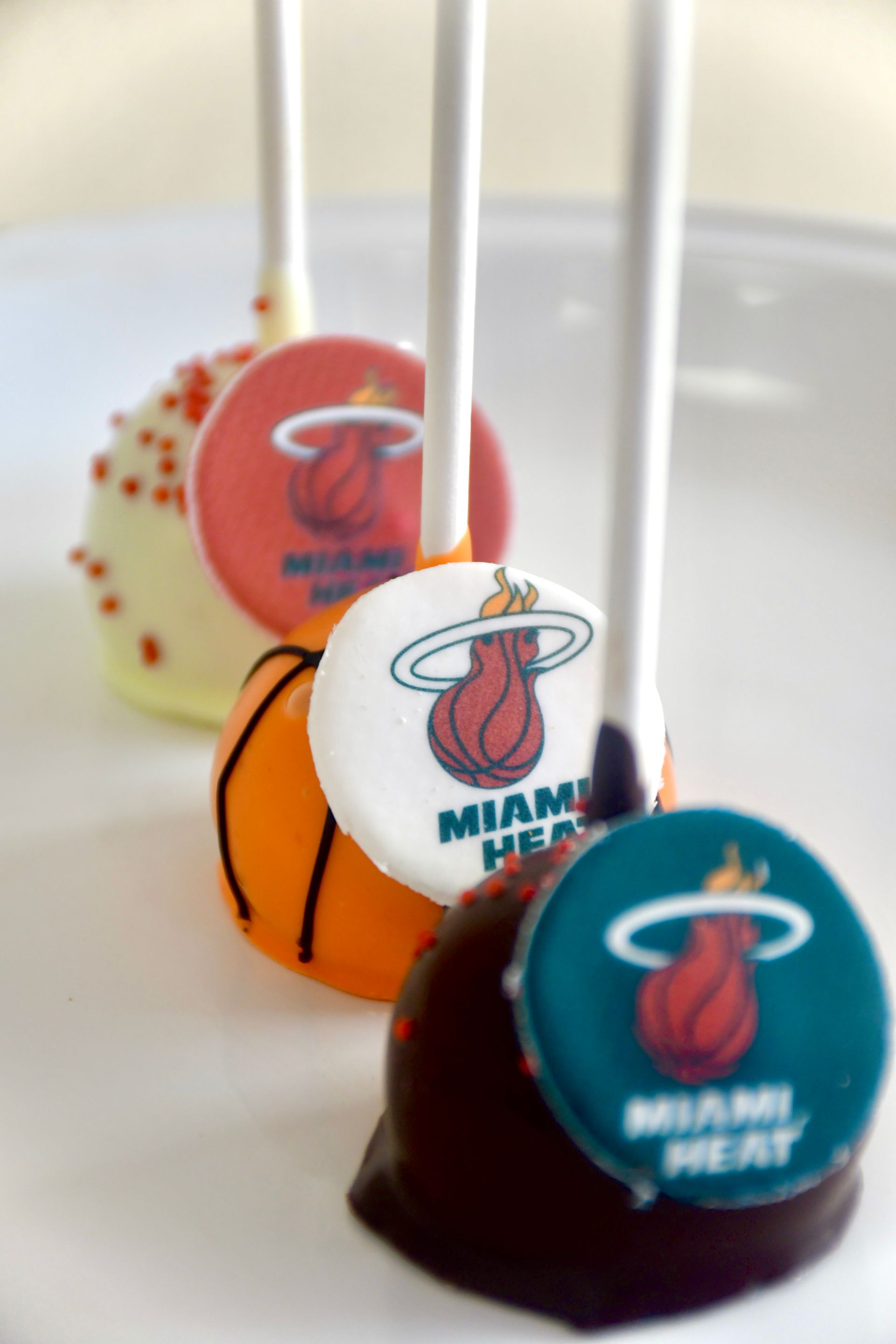 Three miami heat cake pops on a white plate