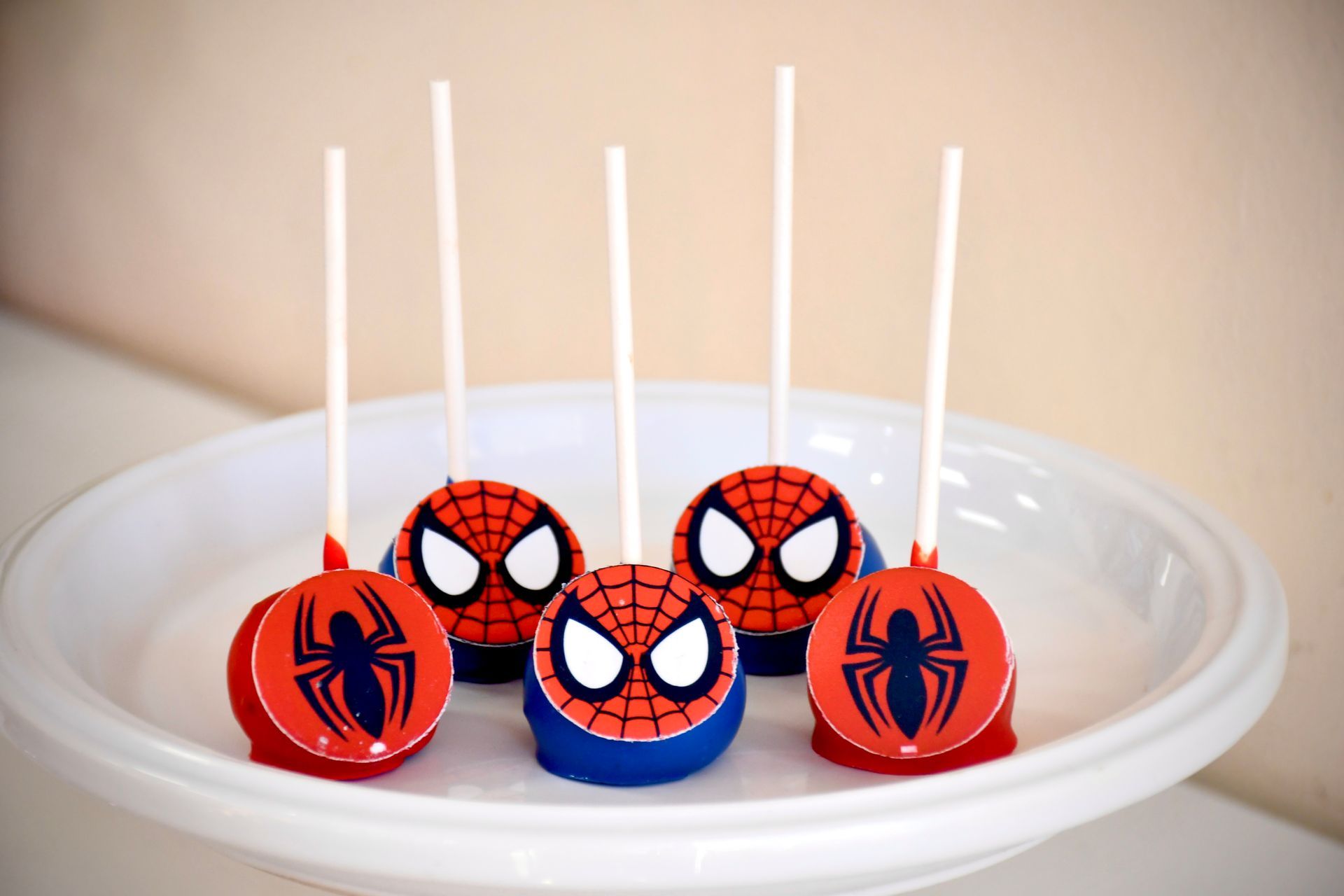A white plate topped with spider man cake pops