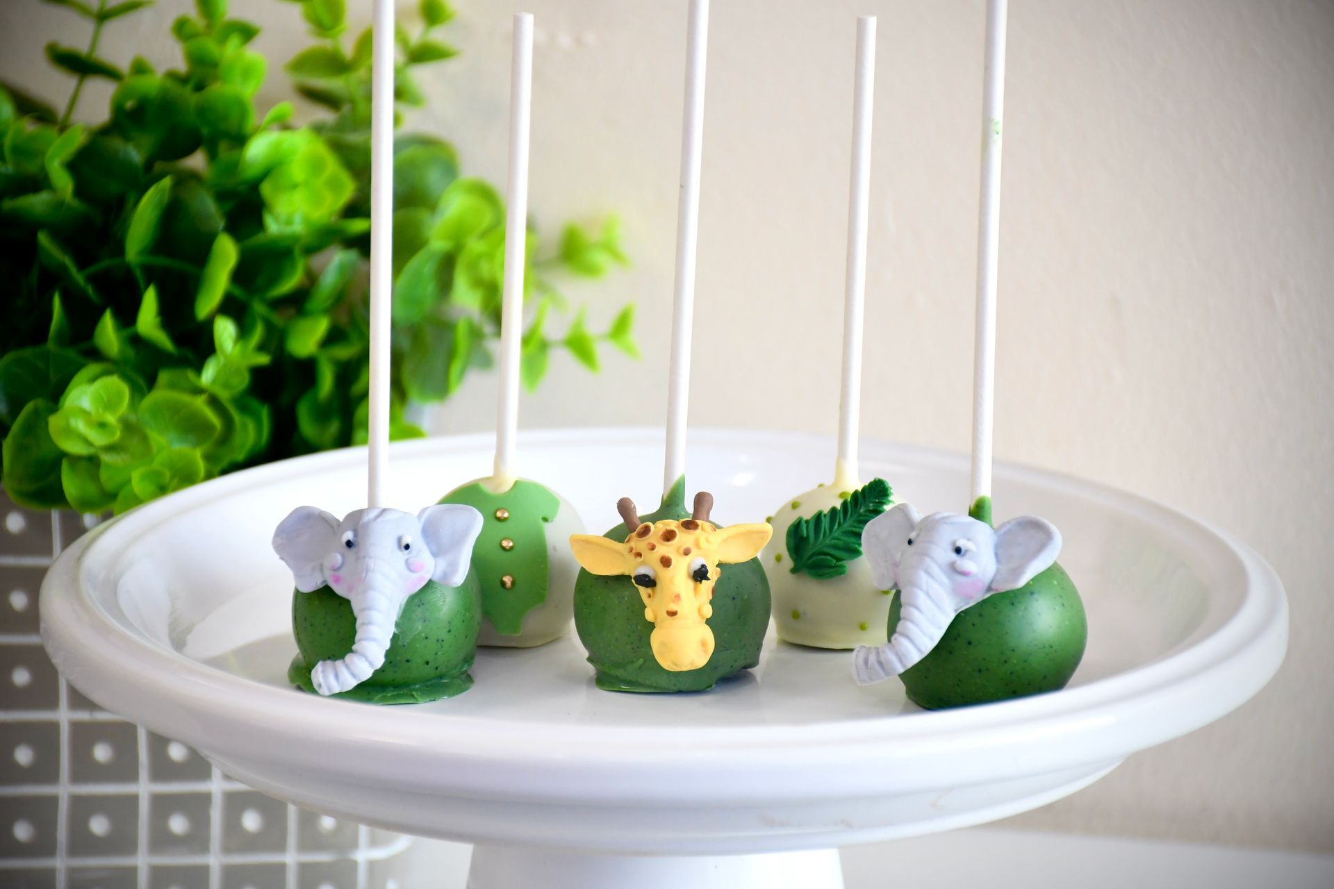 A plate of cake pops with elephants and giraffes on them