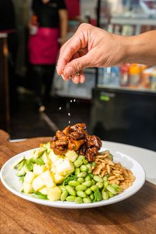 A person is sprinkling salt on a plate of food.