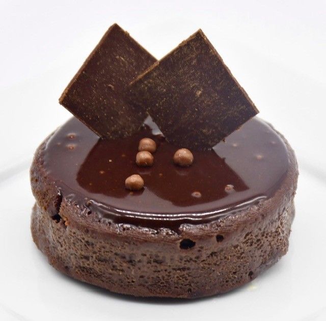 A chocolate cake with squares on top on a white plate