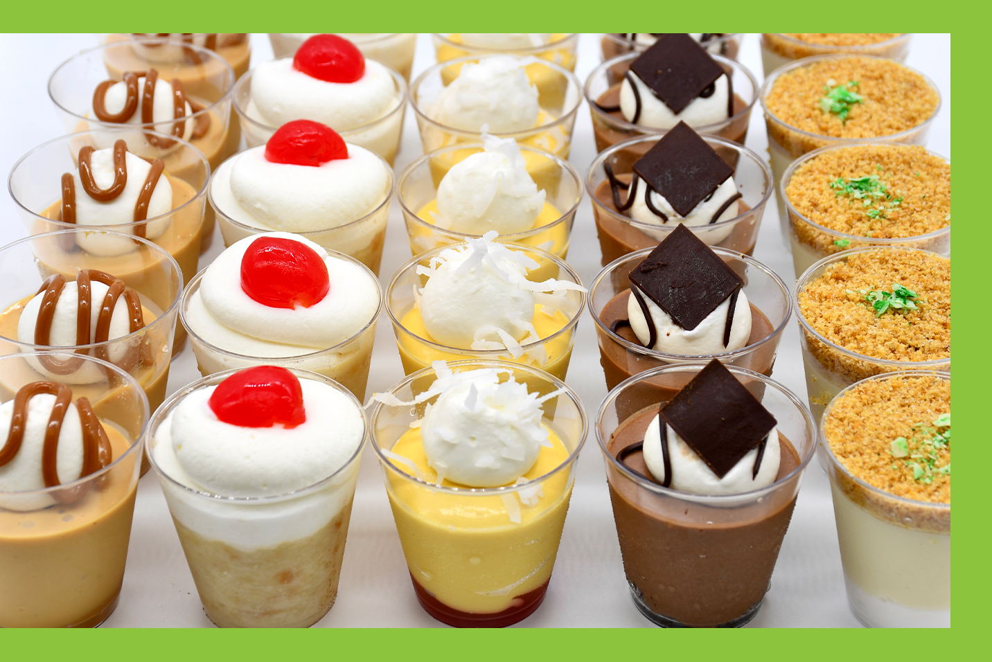 A variety of desserts in plastic cups are lined up on a table.