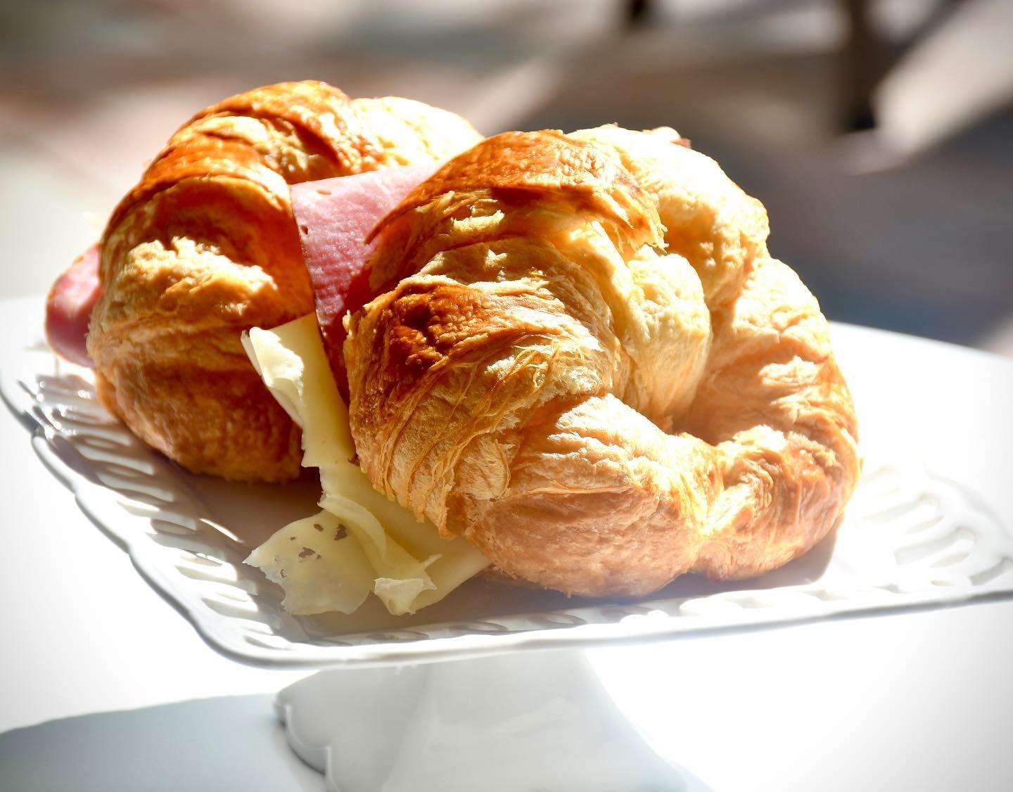 Two croissants with ham and cheese on a white plate